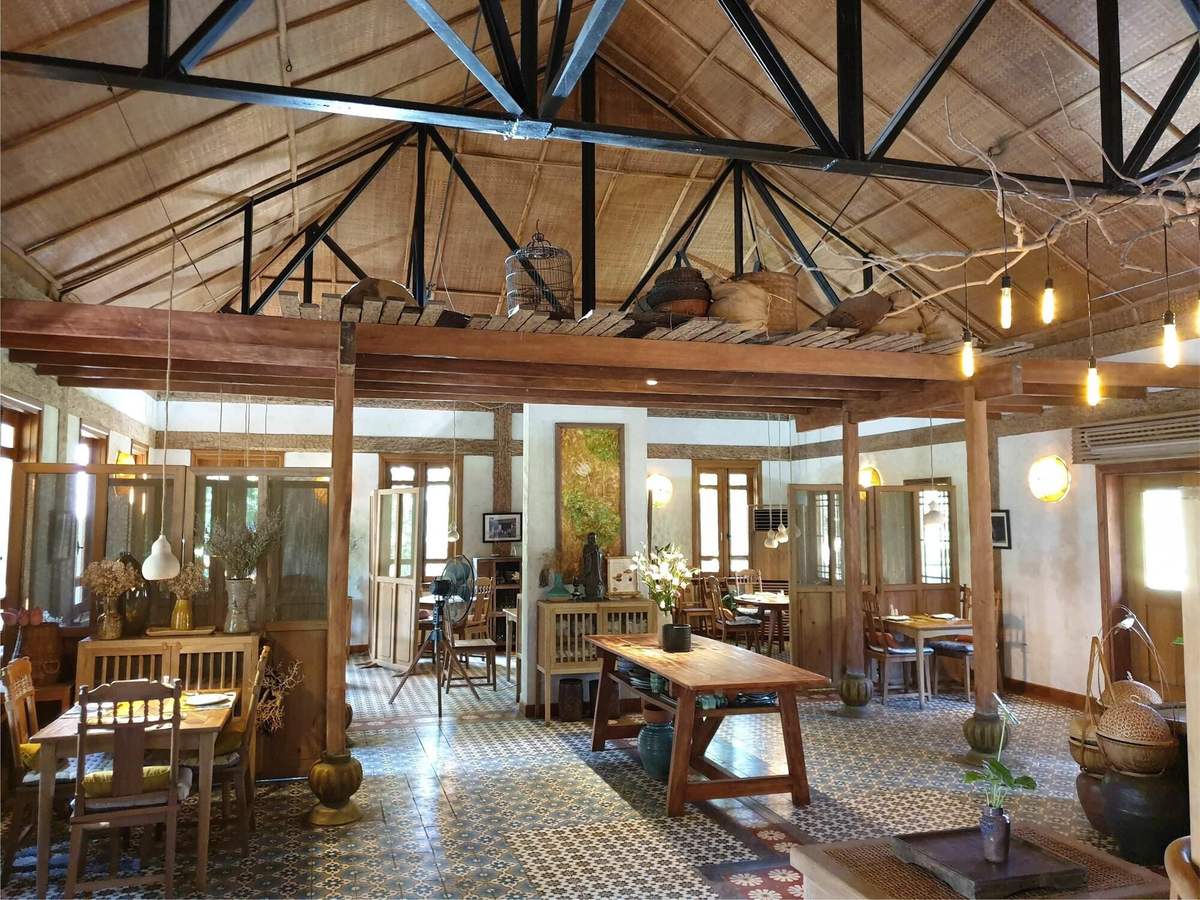 Open-plan lounge and dining room with timber trusses, cement-tile floor and wooden furniture